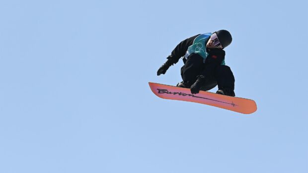 A snowboarder performing a trick high in the air during a snowboarding event