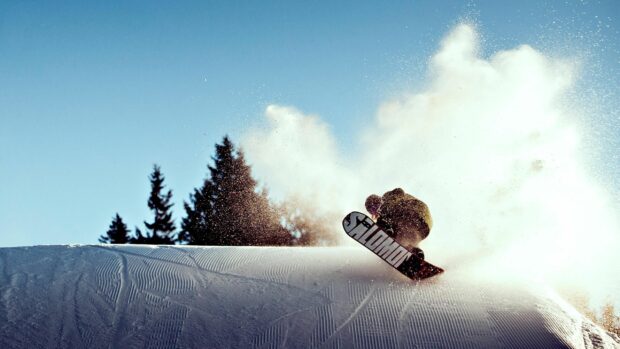 A snowboarder performing a trick on fresh snow with snowboarding gear