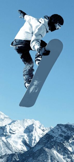 Snowboarder performing a jump against snowy mountain backdrop