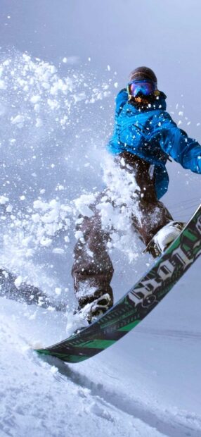 Snowboarding action in fresh powder snow with snowboarder wearing blue jacket