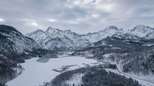 A snowy mountain landscape shows frozen lake and forest in Austria, 4K Desktop Wallpaper