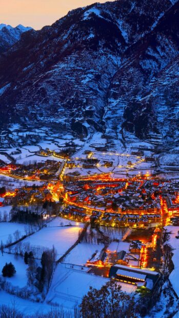 A snowy village under mountain lights showcases Spain wallpapers in winter night, 2K Mobile Wallpaper