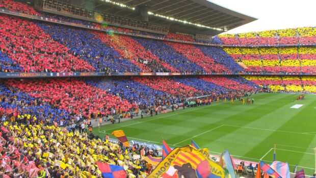 A packed soccer stadium with fans holding colorful cards creating vibrant patterns in the stands