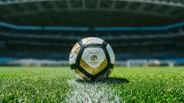 A soccer ball on the grass field in a stadium with the Copa America logo visible