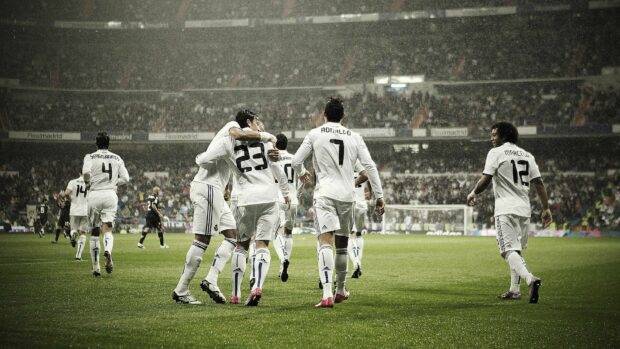 Soccer players celebrating a goal in a soccer match in a crowded stadium