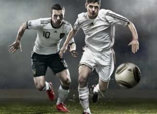 Two soccer players in action chasing a soccer ball on the field