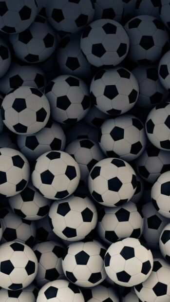 A pile of soccer balls stacked together showing the classic pattern of soccer balls