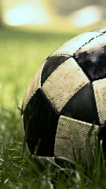 A close up of soccer ball on green grass showing detailed texture and wear