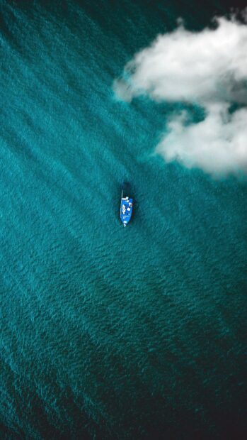 A solitary boat floats on the deep blue water with clouds overhead in Malawi Wallpapers, 4K Mobile Wallpaper