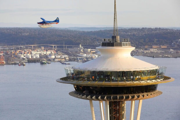 Visitors enjoying the view at Space Needle observation deck with a small plane flying nearby