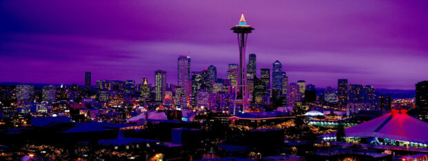 Night cityscape featuring the Space Needle tower in Seattle with bright lights and purple sky