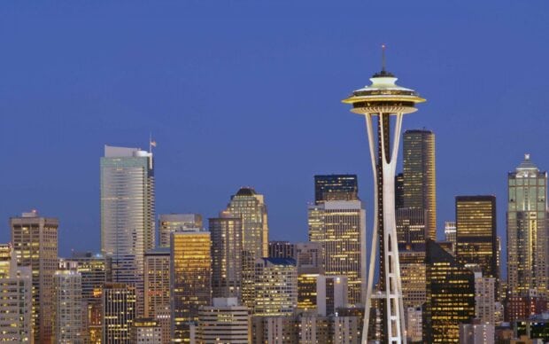 The iconic Space Needle stands tall among illuminated skyscrapers in the Seattle cityscape at dusk