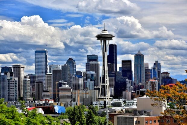 The Space Needle stands tall among the Seattle city skyline on a bright day