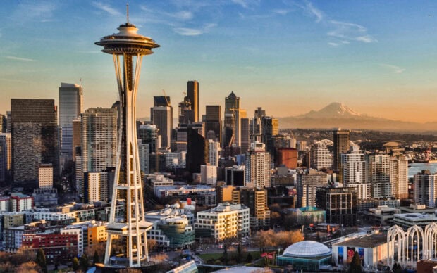 Space Needle in Seattle cityscape during sunset with mountain in background