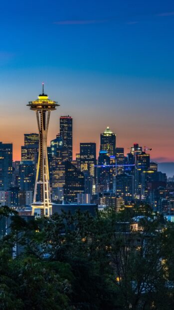 Space Needle illuminated at dusk with Seattle city skyline in the background