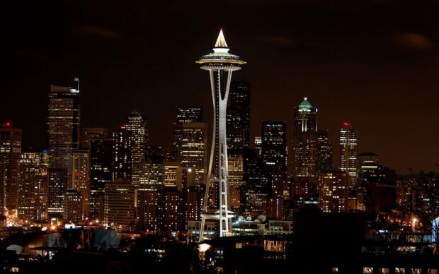 The Space Needle stands tall among the illuminated buildings of the Seattle night skyline