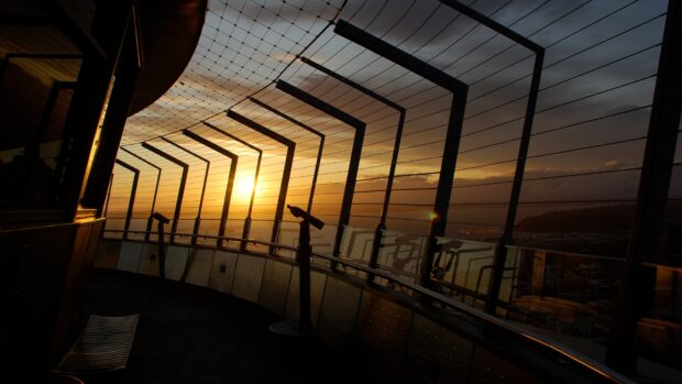 Sunset view from Space Needle observation deck showing safety netting and telescopes