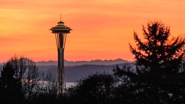 Evening view of the Space Needle with trees and mountains in the background