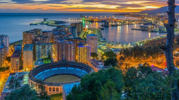 The Spain cityscape at sunset shows a coastal port and urban buildings under a colorful sky, 4K Desktop Wallpaper