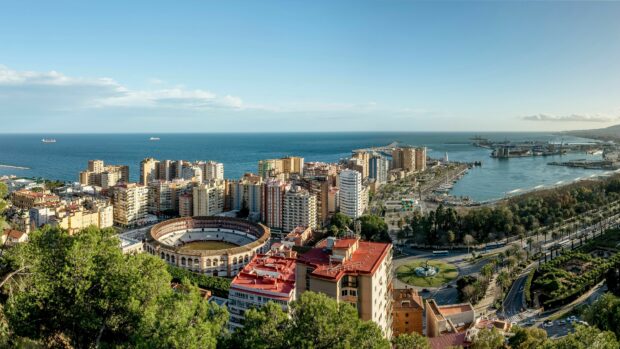 The Spain cityscape shows a coastal view with a historic bullring and tall buildings near the sea, 4K Desktop Wallpaper