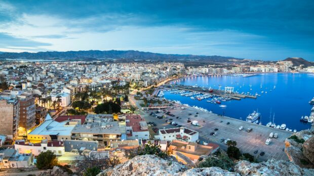The Spain cityscape shows a coastal area with buildings, boats, and mountains in the background, 4K Desktop Wallpaper