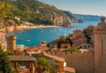 A scenic view of Spain coastline featuring historic castle towers and the blue sea, 4K Desktop Wallpaper