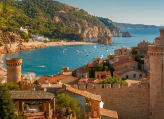 A scenic view of Spain coastline featuring historic castle towers and the blue sea, 4K Desktop Wallpaper