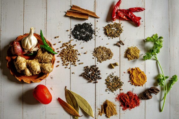 Various spices including ginger and dried chili arranged on a wooden table