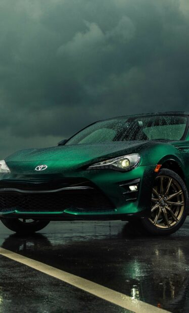 Green sports car under rainy dark sky.