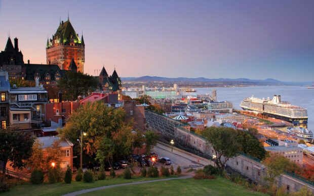 Sunset view of St Lawrence River with city buildings and a large cruise ship docked at the port
