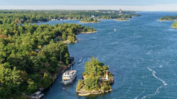 A high resolution wallpaper of the St Lawrence River with a boat sailing between lush green islands