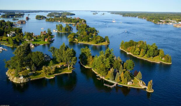 Aerial view of the St Lawrence River with lush green islands and clear blue water under a sunny sky