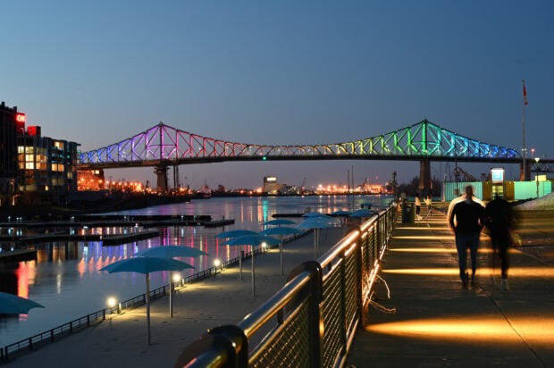 Night view of St Lawrence River with colorful lit bridge and waterfront walkway