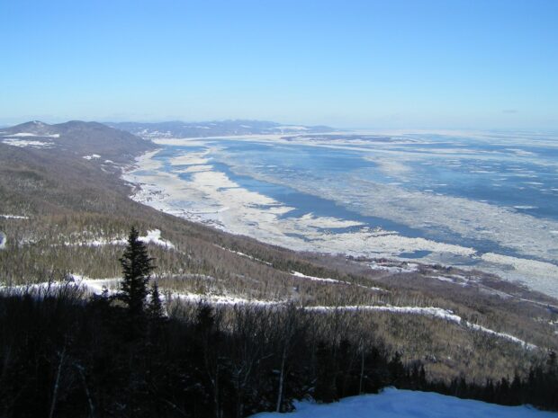 Panoramic view of the frozen St Lawrence River and snow covered landscape under a clear blue sky