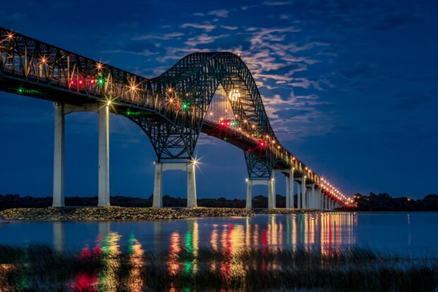 A night view of the illuminated bridge over the St Lawrence River reflecting colorful lights on the water