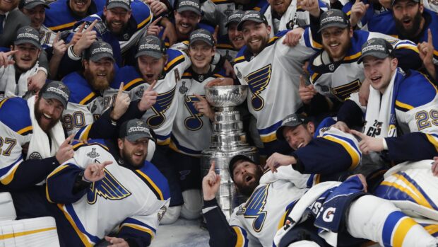The St Louis Blues players gather around the Stanley Cup trophy in celebration, 4K Desktop Wallpaper