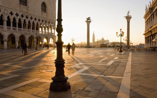 A couple walks through St Marks Square with historic buildings and columns around them, HD Desktop Wallpaper