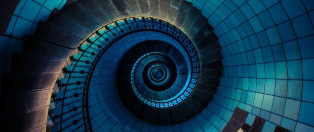 Spiral staircase with blue tiled walls and metal railing viewed from above