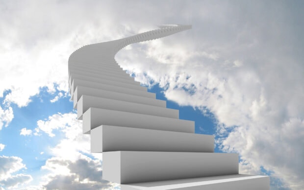 A curved staircase reaching into the sky with clouds surrounding the structure