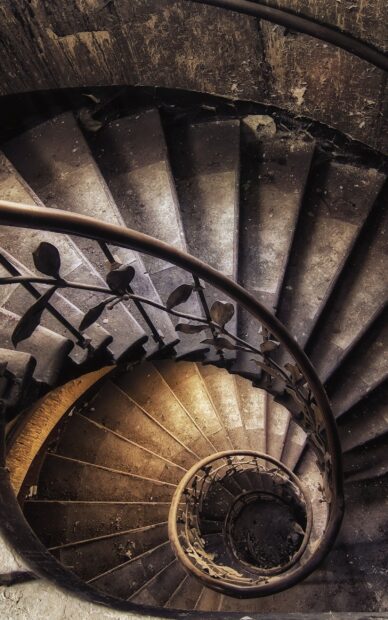 Spiral staircase with intricate metal railing in an old building viewed from above