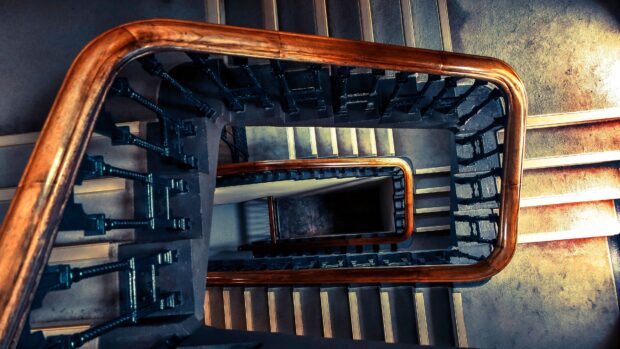 A spiral staircase with wooden handrails viewed from above in a narrow staircase
