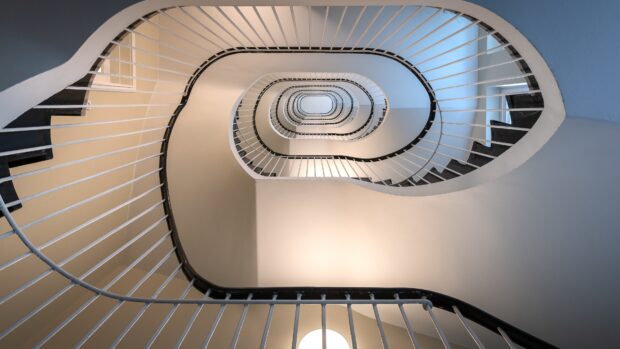 Spiral staircase seen from below with metal railings and soft lighting