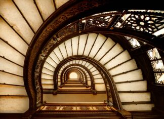 Vintage spiral staircase with ornate railing viewed from below interior design