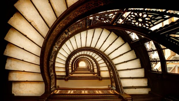 Vintage spiral staircase with ornate railing viewed from below interior design