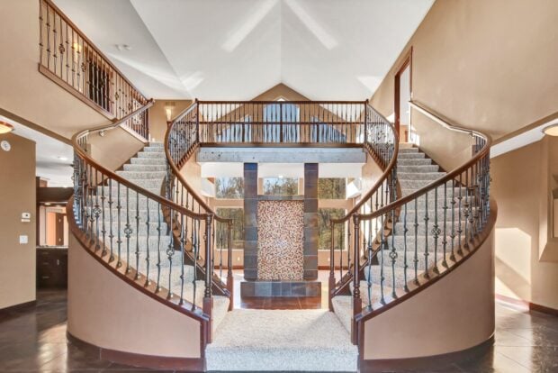 Elegant curved staircase with carpeted steps and wooden railing in a spacious home interior