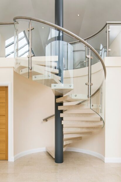 Modern spiral staircase with glass and metal railing in a bright interior