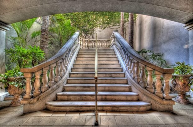 Classic staircase with stone balusters and tropical plants lining each side