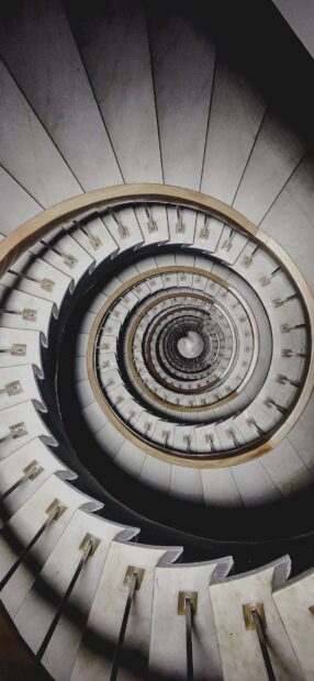 Spiral staircase design with vintage handrail and concrete steps viewed from above