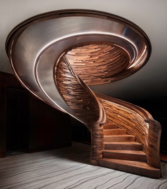 A modern wooden staircase design with a smooth curved shape and ambient lighting