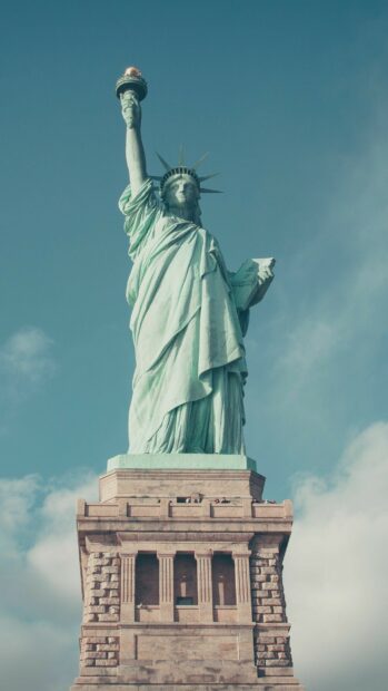 The Statue of Liberty stands tall against a blue sky in this iconic view, 2K Mobile Wallpaper